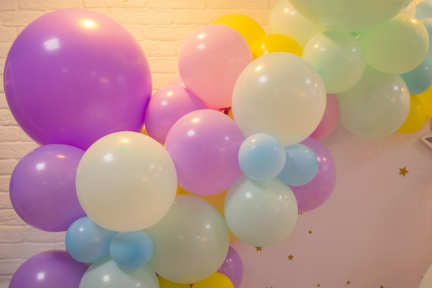 Am Geländer der Veranda sind Ballons befestigt. Eröffnung des Ladens. Cremefarbene Wand, rote Treppe. Helles Sonnenlicht und Schatten. Festlicher Straßenhintergrund.