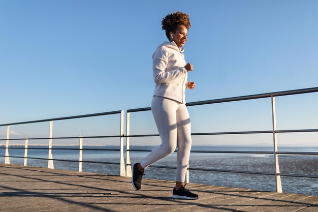 Foto am meer joggt eine junge schwarze frau auf einem holzsteg am meer