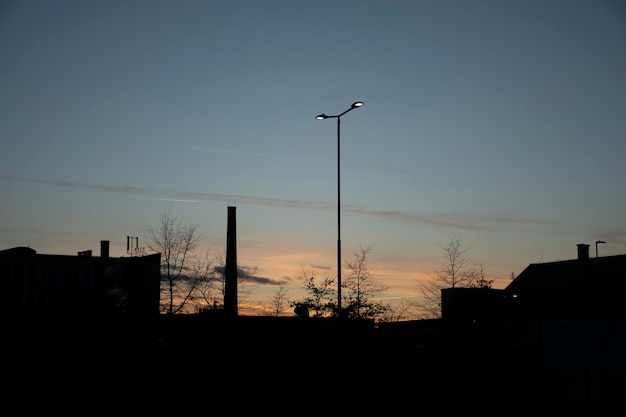 Am späten Nachmittag Silhouette der Stadt mit Sonnenuntergang und einer beleuchteten Straßenlaterne