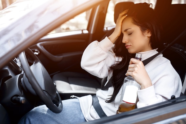 Am Steuer trinken. Eine betrunkene Frau fährt Auto.