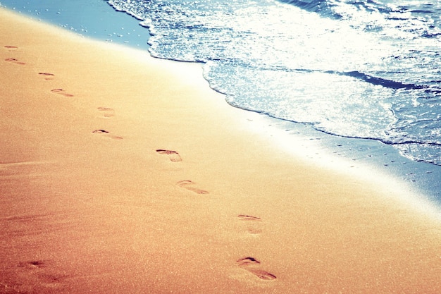 Foto am strand spazieren gehen und fußspuren im sand hinterlassen