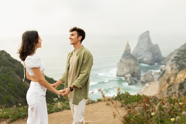 Am Strand verbindet sich ein junges verliebtes europäisches Paar, das ein romantisches Date hat und Händchen hält