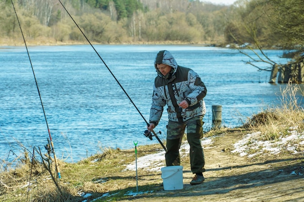 Foto am ufer des sees angelt ein fischer mit einer stange in der hand.