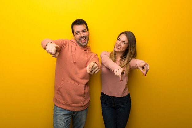 Am Valentinstag Gruppe von zwei Personen auf gelbem Hintergrund zeigt Finger auf Sie beim Lächeln