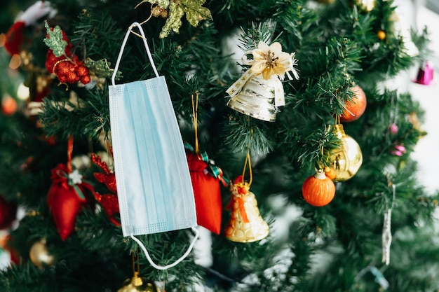 Am Weihnachtsbaum wurden medizinische Corona-Virus-Gesichtsmasken aufgehängt. Frohe Weihnachten in der Covid-19-Pandemie.