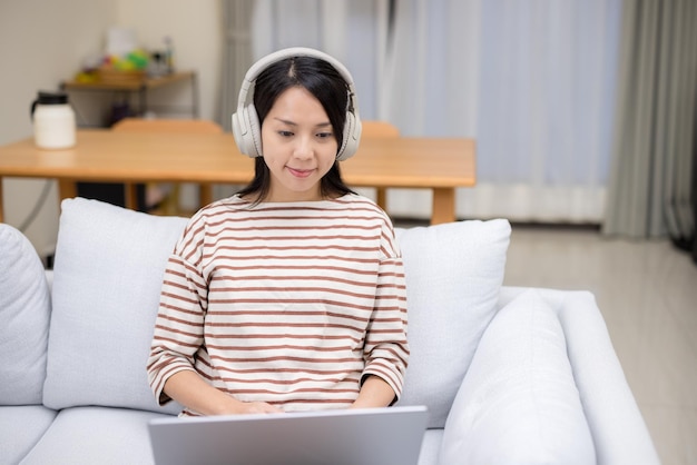 Ama de casa con auriculares y trabajo en computadora portátil en casa