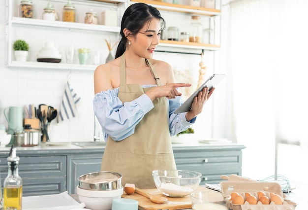 ama de casa en la cocina usando una tableta para buscar recetas en línea cocinando la masa de panadería casera