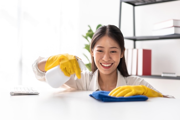 Ama de casa en delantal con guantes para rociar spray de higiene en t