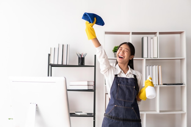 Ama de casa en delantal con guantes para sostener la botella de spray de higiene