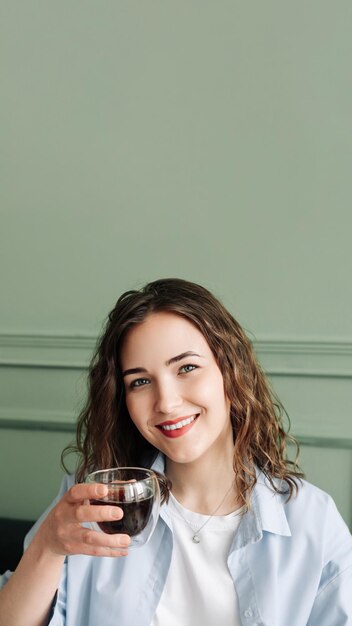 Ama de casa joven feliz disfrutando de un descanso acogedor con té caliente en el sofá en casa dama sonriente