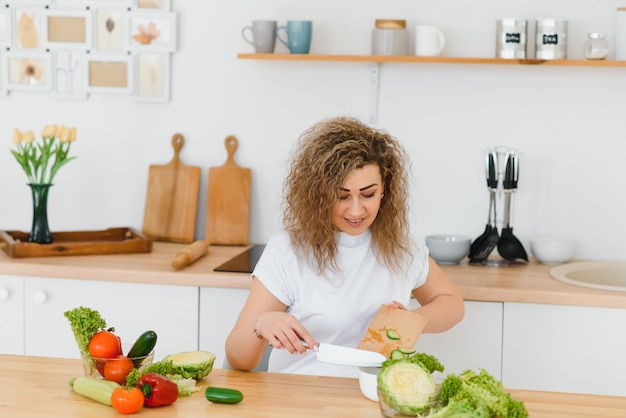 Ama de casa joven feliz mezclando ensalada de verduras