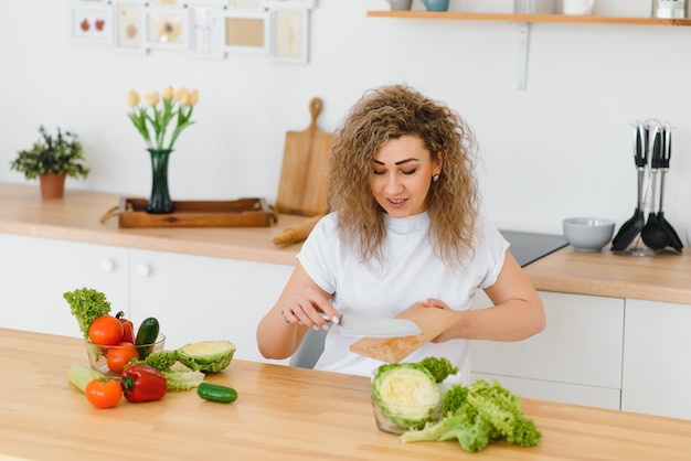 Ama de casa joven feliz mezclando ensalada de verduras