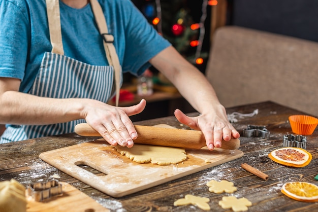 Ama de casa joven hace masa para cocinar galletas de jengibre festivas