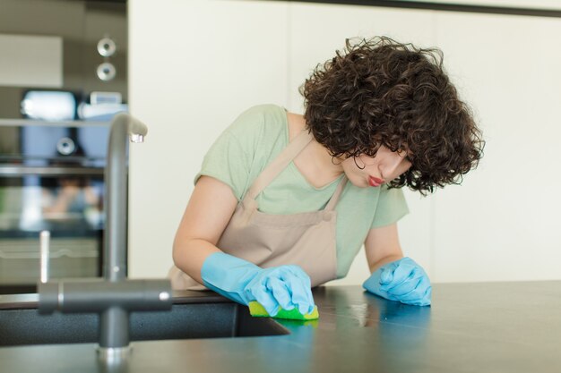 Ama de casa de mujer bonita joven lavando platos en casa