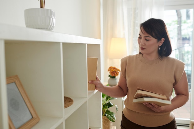 Ama de casa poniendo libros en estantería