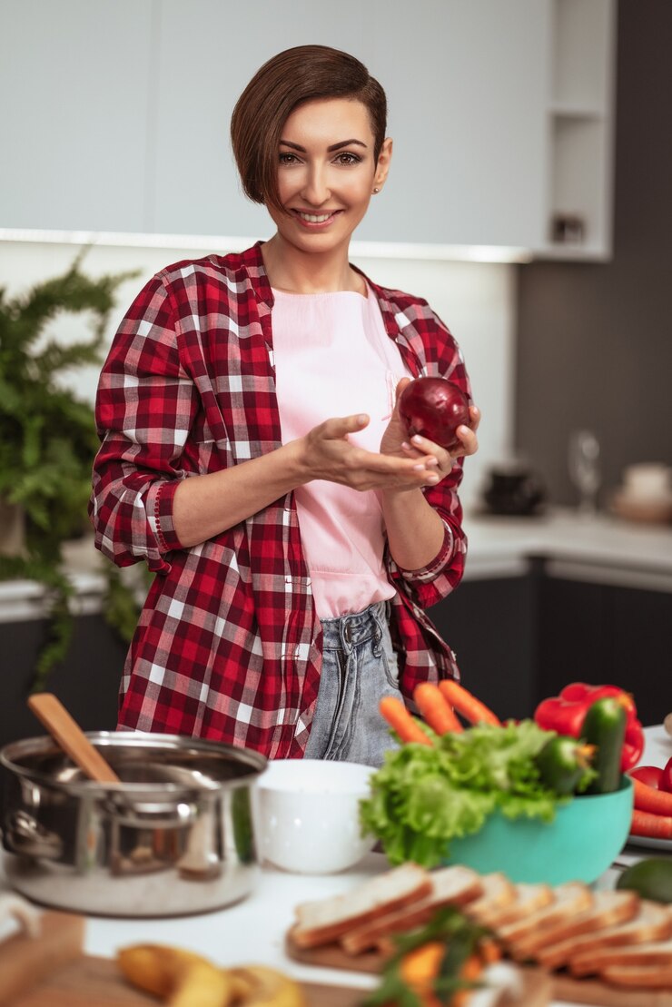 Foto ama de casa prepara la cena para la familia eligiendo verduras sosteniendo una cebolla roja en manos de pie