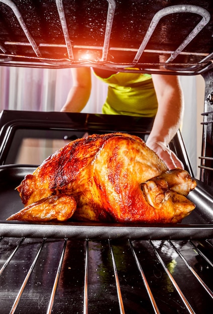 El ama de casa prepara pollo asado en el horno, vista desde el interior del horno. Cocinar en el horno. Día de Gracias.