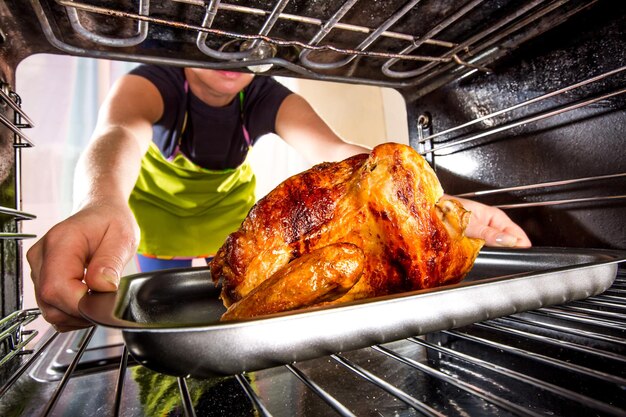 El ama de casa prepara pollo asado en el horno, vista desde el interior del horno. Cocinar en el horno.