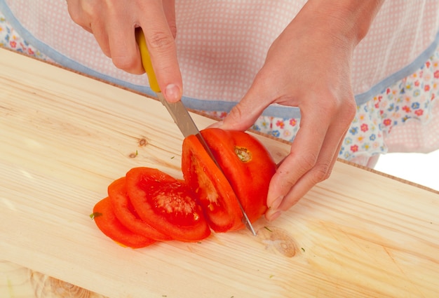 Ama de casa preparando tomate. Estudio, fondo blanco.