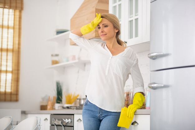 Ama de casa rubia en guantes protectores sintiéndose mal