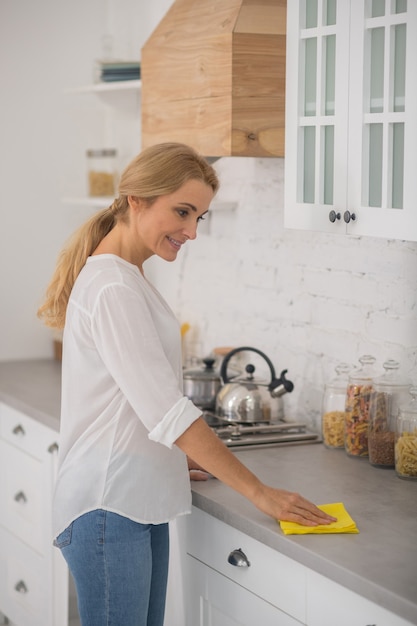 Foto ama de casa rubia linda limpiando en la cocina