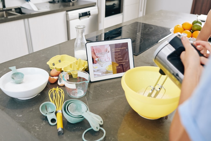 Foto ama de casa siguiendo la receta en la computadora de la tableta y mezclando los ingredientes en un recipiente de plástico