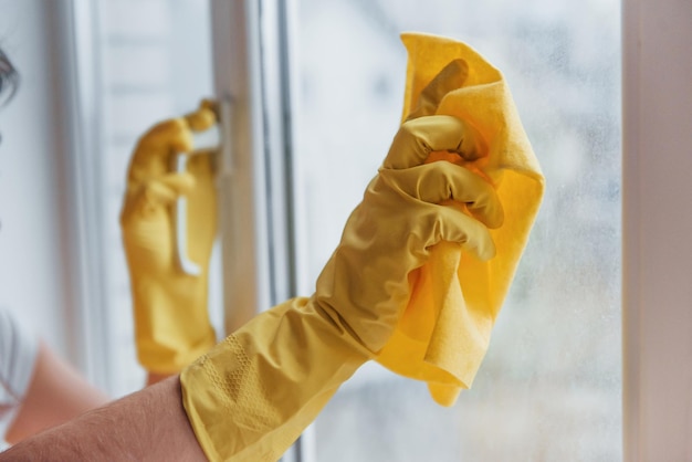 Ama de casa en uniforme amarillo limpiando ventanas Concepción de renovación de la casa