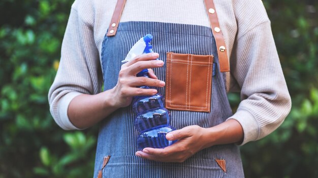 Foto una ama de llaves con delantal sosteniendo una botella de spray en el jardín