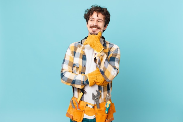 Ama de llaves joven manitas sonriendo con una expresión feliz y segura con la mano en la barbilla