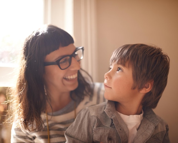 Ama a la madre y al hijo uniendo la felicidad y la conversación en casa divertida y riendo Padre femenino de la familia y mamá feliz con un niño varón y un niño con alegría amando y relajándose en una sala de estar