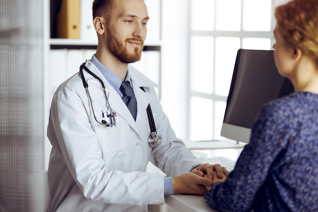 Amable doctor de barba roja tranquilizando a su paciente. Ética médica y concepto de confianza, tema de la medicina.