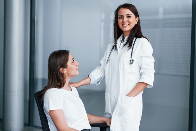 Amable doctor escuchando al paciente Mujer joven tiene una visita con doctora en clínica moderna