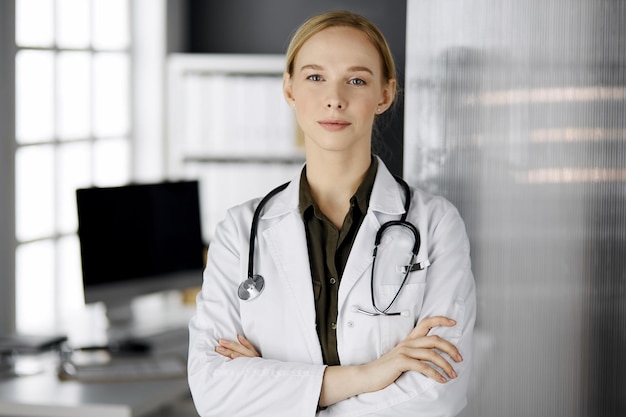 Amable doctora sonriente de pie en la clínica. Retrato de mujer médico amable. Servicio médico perfecto en el hospital.