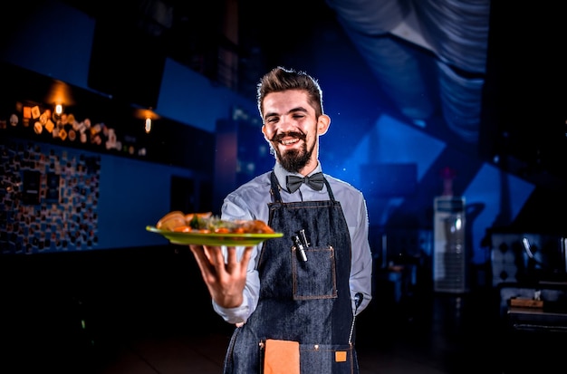 El amable empleado del restaurante tiene un plato cocinado en un evento festivo.