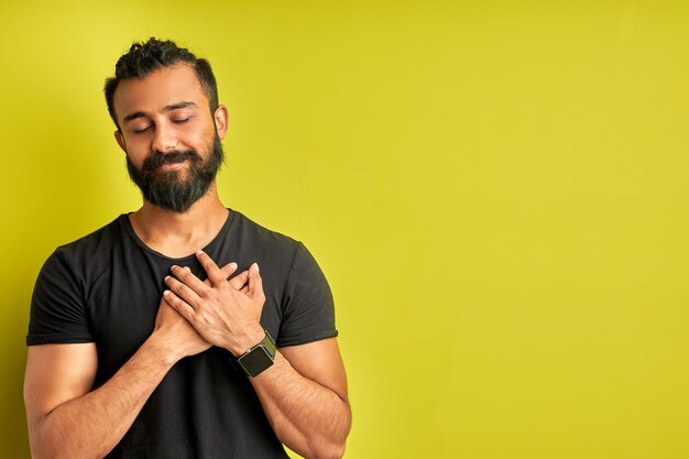 Amable hombre árabe está agradecido por algo aislado sobre fondo verde