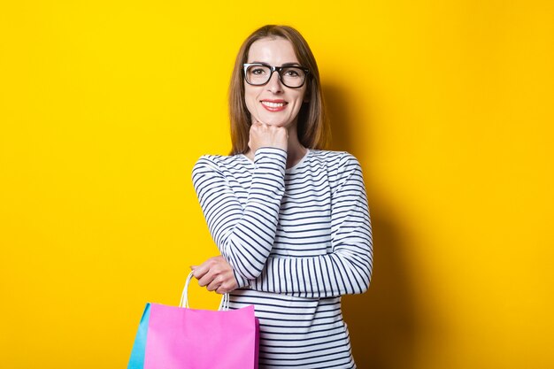 Amable joven sonriente con bolsas de la compra sobre un fondo amarillo