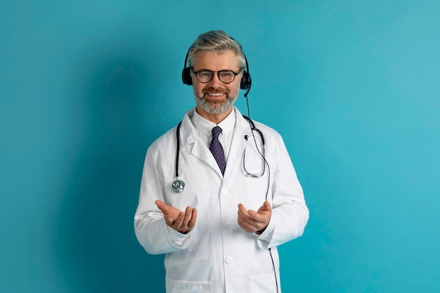 Amable médico europeo con auriculares sobre fondo azul de estudio