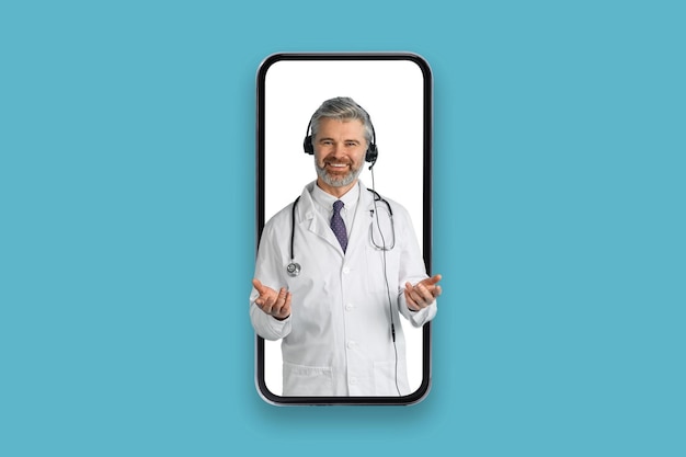 Foto amable médico de mediana edad con auriculares en pantalla de teléfono grande