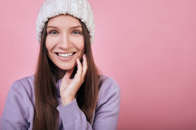 Amable mujer lleva un gorro de punto blanco y un suéter delicadamente púrpura