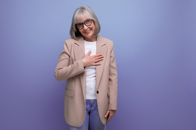 Amable mujer de mediana edad en una chaqueta muestra un corazón con las manos sobre un fondo brillante con copia