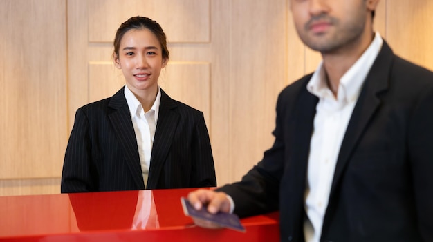 Amable recepcionista mujer trabajando en el escritorio en el vestíbulo del hotel Ocio y viajes en vacaciones hermosa joven asiática recepcionistas trabajando en un mostrador de recepción