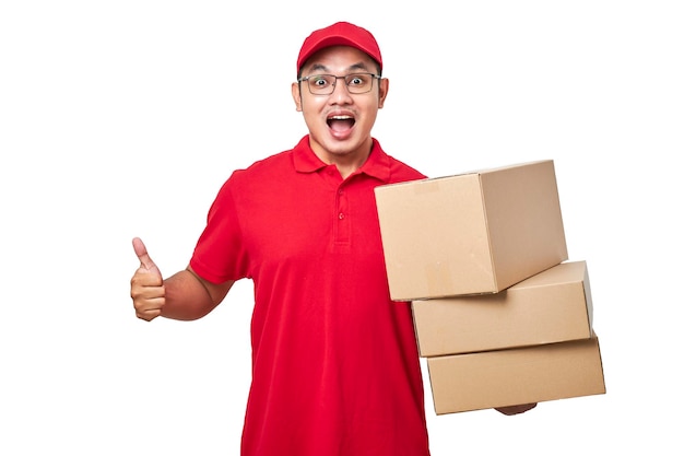 Amable repartidor de mensajería asiático con camisa roja y gorra que muestra el pulgar hacia arriba sosteniendo el paquete de la caja con la mano