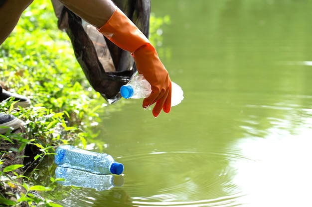 Amables voluntarios ecológicos sosteniendo paquetes y recolectando botellas plásticas de basura del agua.