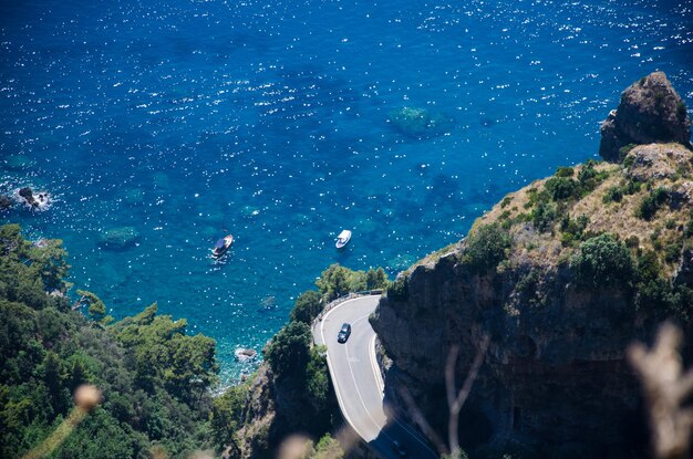 Foto amalfi-küste - detail der haarnadelbiegung klippe türkisfarbenes meer und boote aussicht vom weg der götter