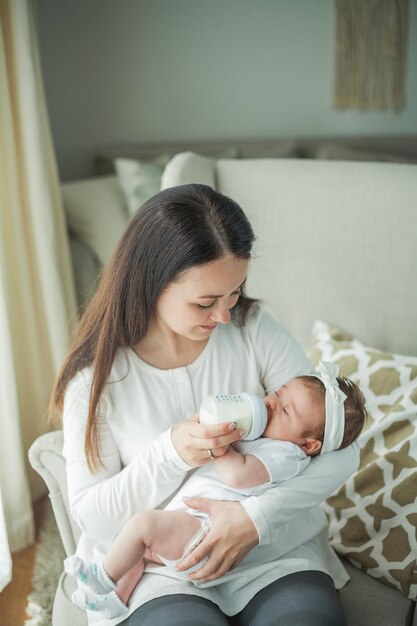 Amamentação Linda jovem mãe está alimentando com mamadeira seu bebê de 2 meses Mistura de bebê Leite materno Maternidade