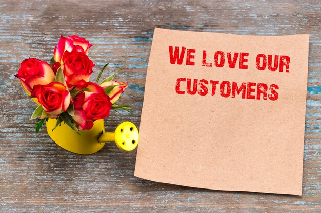 Amamos a nuestros clientes - inscripción en hoja de papel vintage y ramo de rosas.