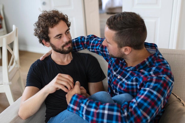 Amando casal gay masculino do mesmo sexo deitado no sofá em casa e relaxando abraçados juntos