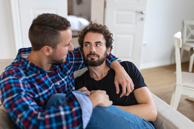 Amando casal gay masculino do mesmo sexo deitado no sofá em casa e relaxando abraçados juntos