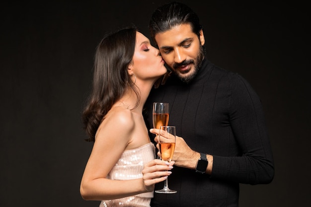 Amando jovem casal multicultural bebendo champanhe em fundo preto