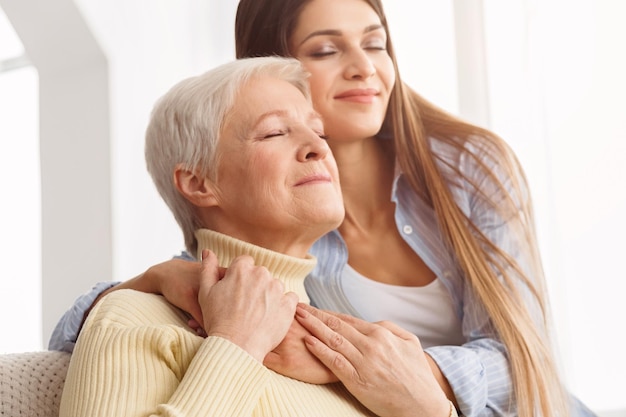 Amando mãe mais velha e filha abraçando em casa